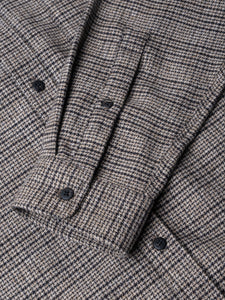 The cuff of a men's long sleeve shirt with a micro prince of wales check pattern.