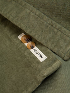 The woven logo patch to the hem of a men's shirt in green moleskin.