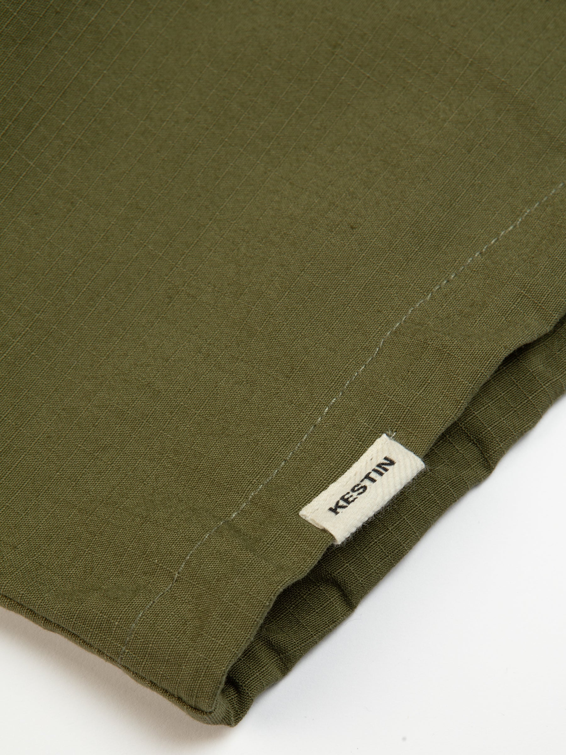 The woven logo tag sewn to the hem of the KESTIN Aberfeldy Windbreaker in Green.