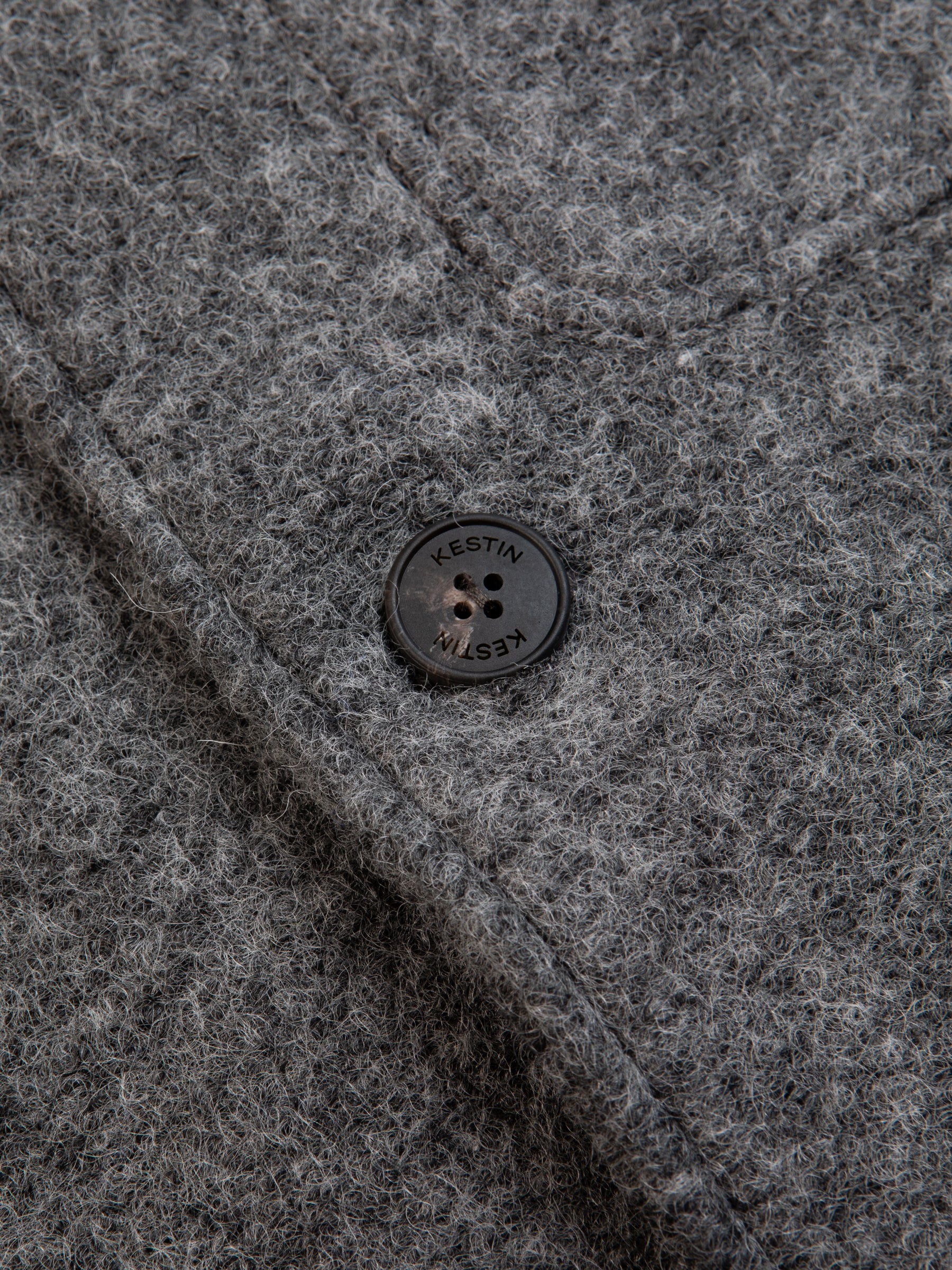 The branded button to the front of the KESTIN Ormiston Jacket in grey wool.