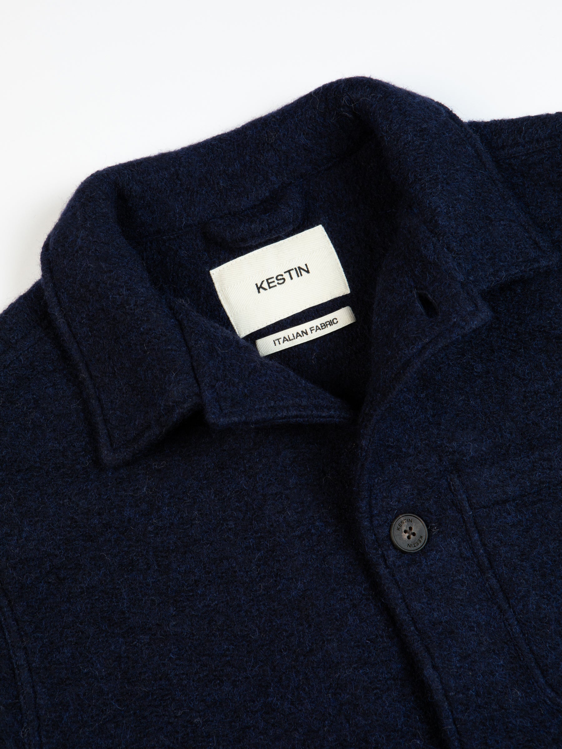 A navy blue fleece jacket from menswear brand KESTIN, with the top button undone.