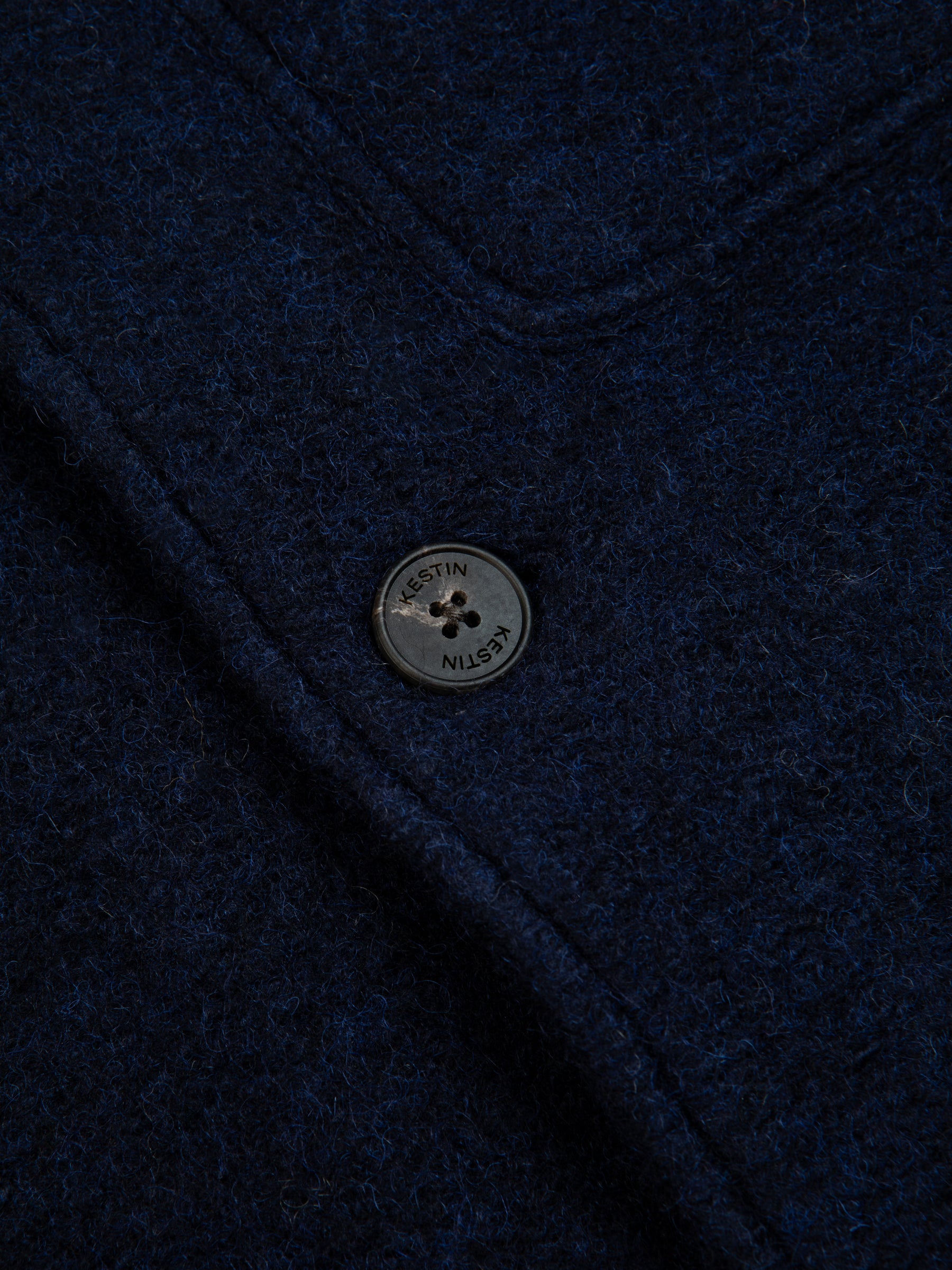 The branded button to the front of the KESTIN Ormiston Jacket in midnight blue.