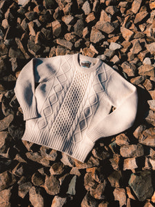 A traditional knitted wool sweater, lying on socks in Scotland.