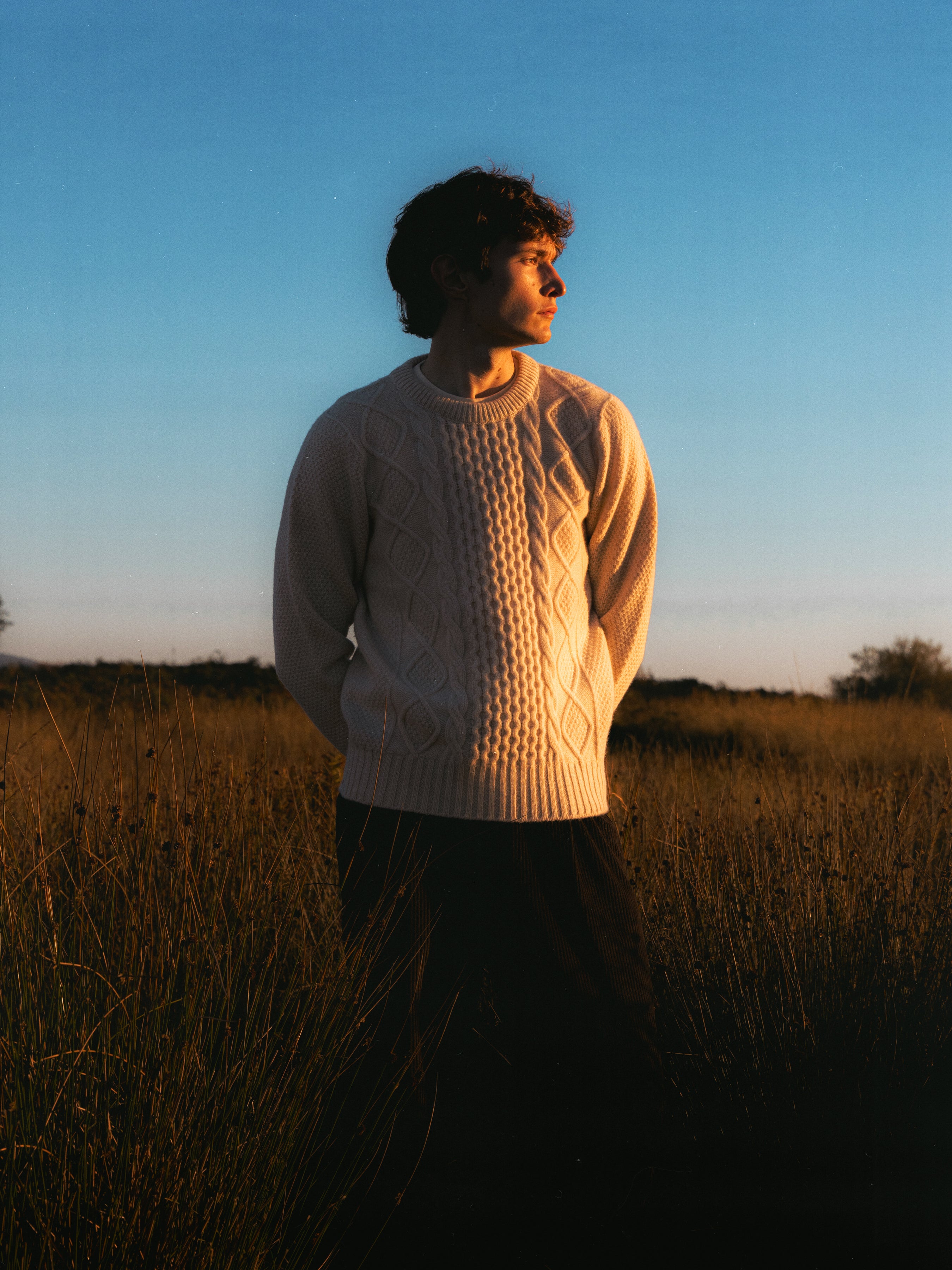 A man wearing a knitted sweater during sunset on the Isle of Arran.