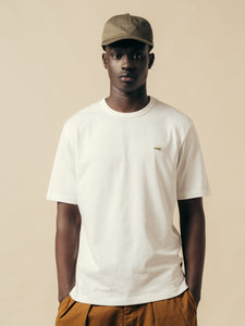 A model wearing a white t-shirt with an embroidered fishing fly to the chest.