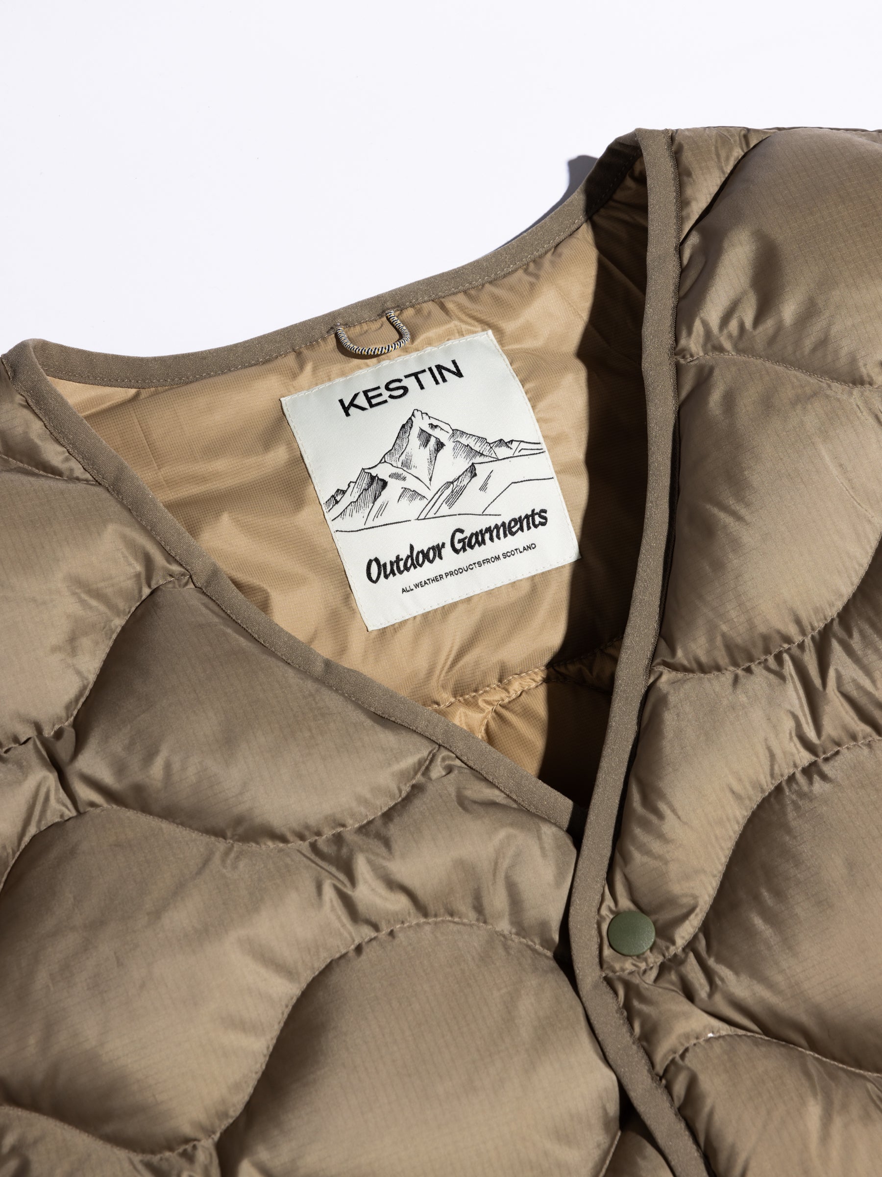 A woven logo patch to the inside of the Cuillin Down Vest in olive green.