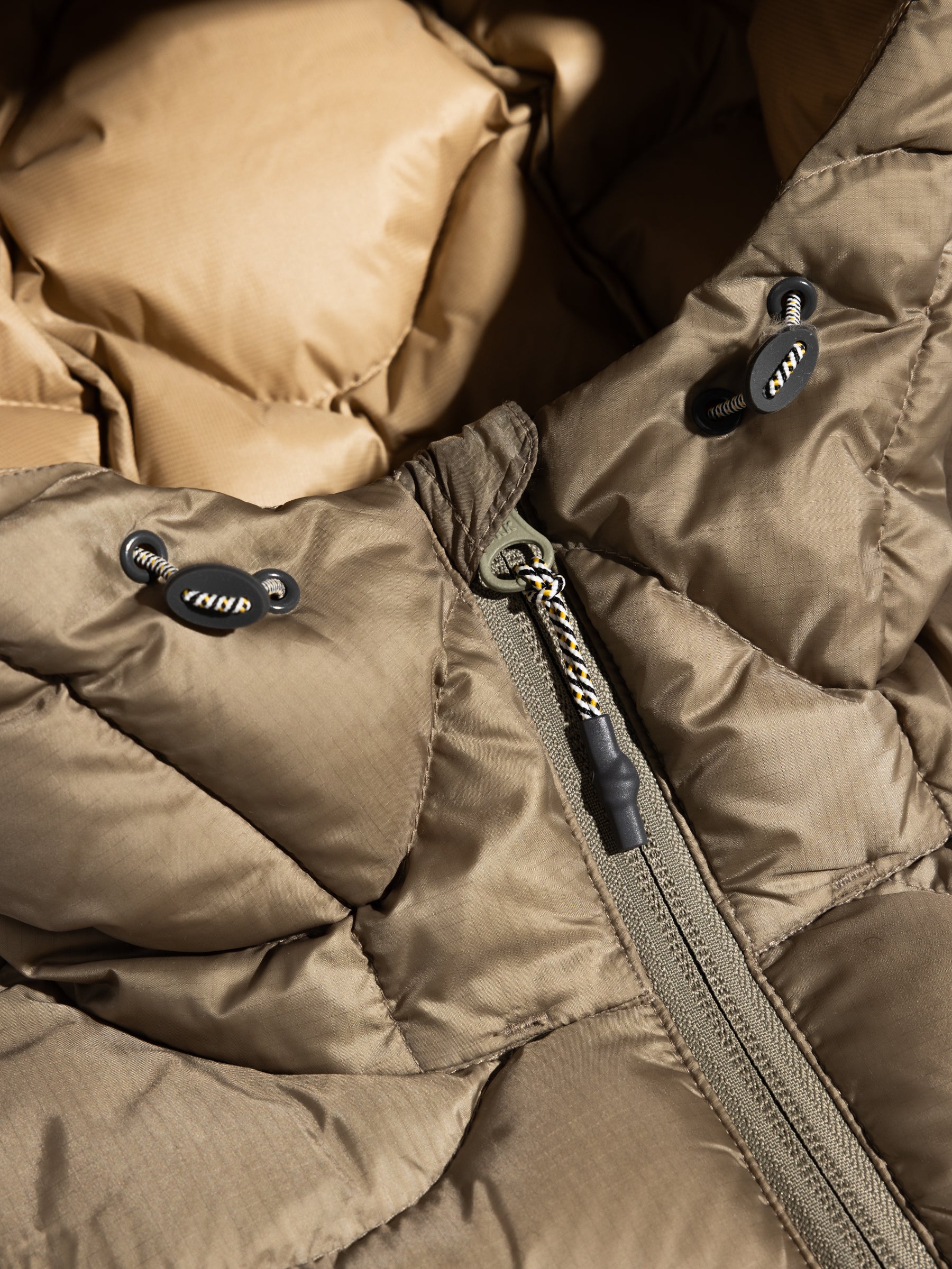 A close-up of the zipper of the KESTIN Cuillin Down Jacket in Olive.