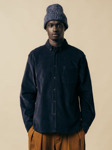 A man wearing a blue shirt and beanie, and brown trousers, from menswear brand KESTIN.