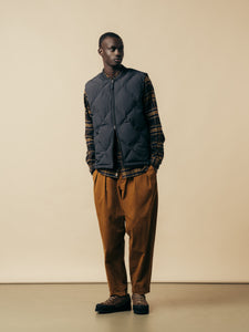 A model wearing a check flannel shirt, an insulted vest and relaxed fit pants.