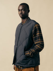 A man wearing a plaid flannel shirt and an insulated gilet from menswear brand KESTIN.