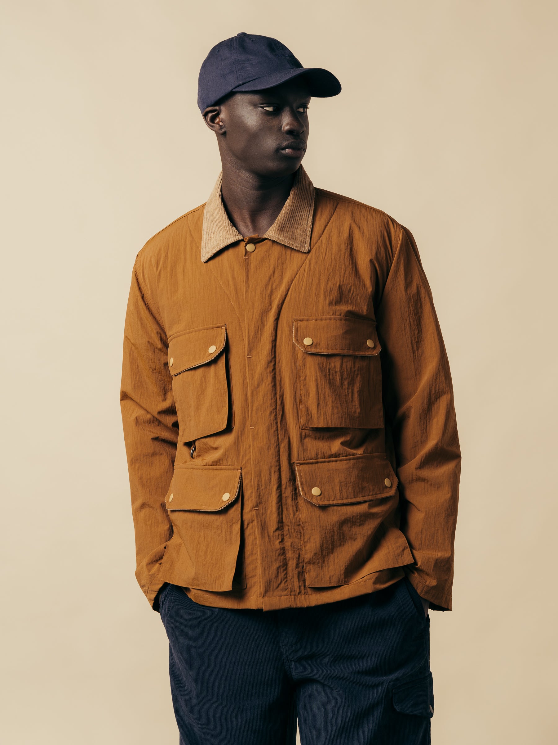 A model wearing a brown jacket with four pockets and a corduroy collar.