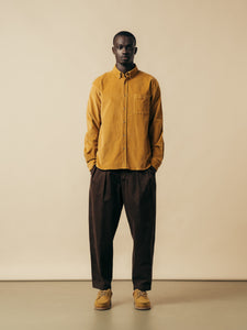 A model wearing a yellow shirt and brown pants, designed by menswear brand KESTIN.