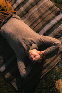 A model lying down on a striped blanket, wearing Scottish knitwear.