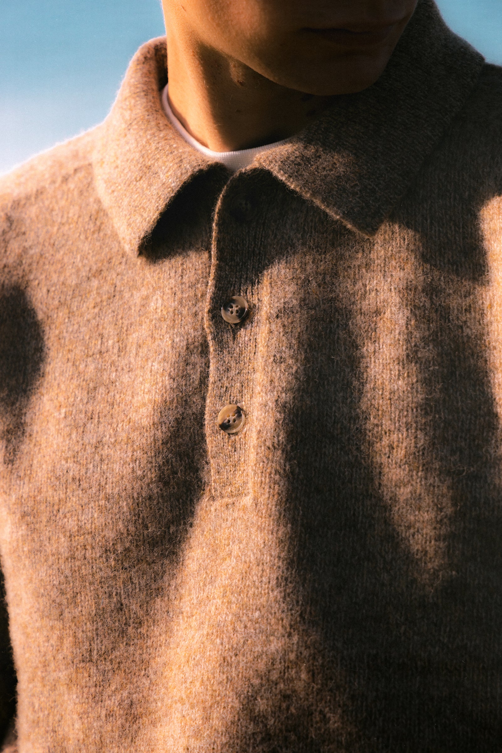 The buttoned neck on a knitted polo sweater, made in Scotland.