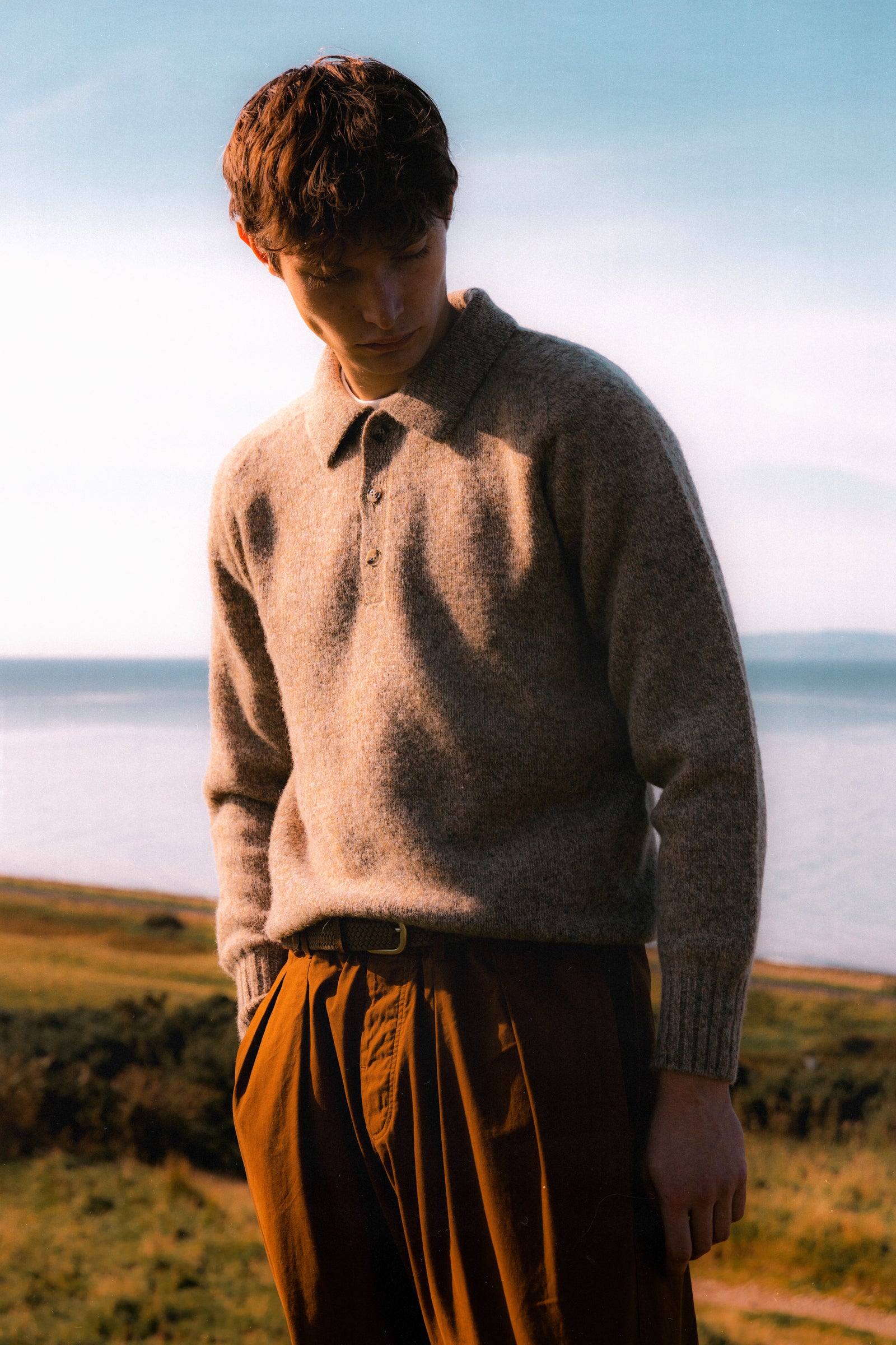 A model wearing a knitted wool polo sweater in beige.