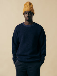 A model wearing a navy blue fleece and a yellow beanie.