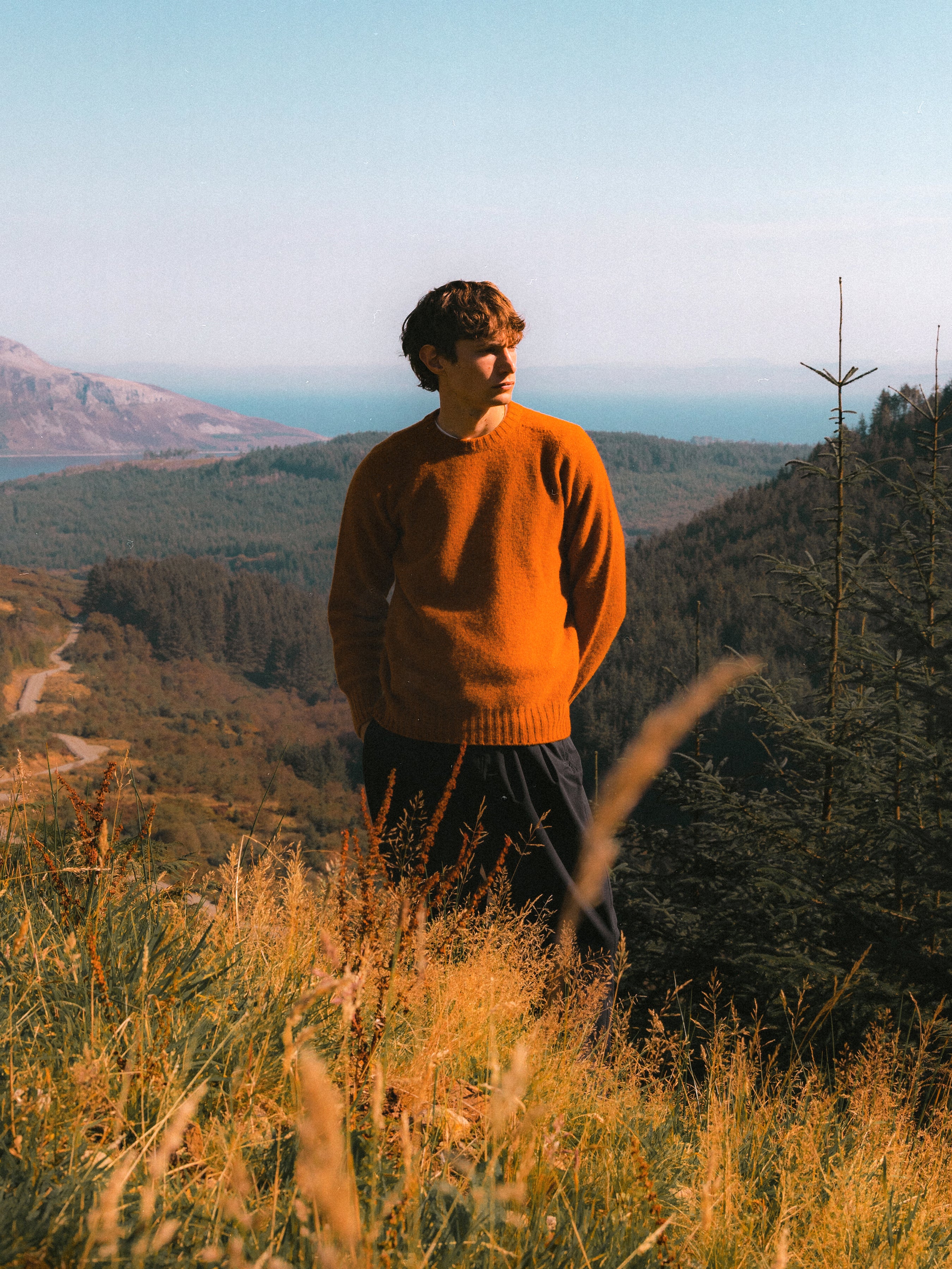 A model standing on the Isle of Arran, wearing an orange sweater.