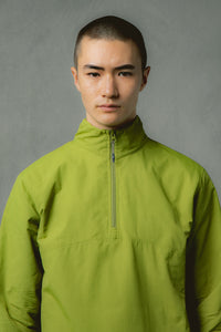 A model wearing a zip neck jacket in bright green, made from nylon ripstop.