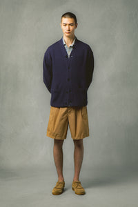 A model wearing a navy cardigan and tan brown shorts from menswear brand KESTIN.