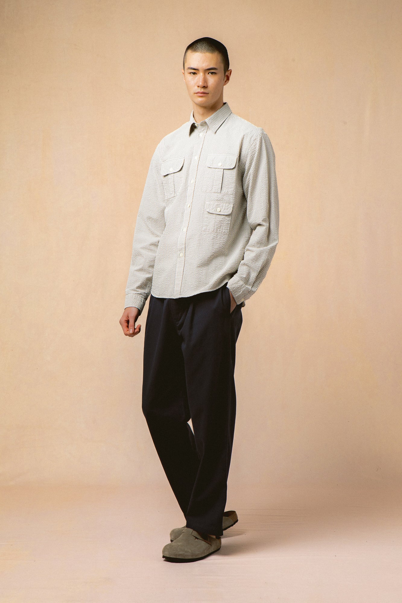 A model wearing a three-pocket utility shirt in a blue stripe seersucker.