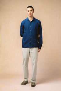 A model wearing an indigo blue shirt and seersucker trousers from menswear brand KESTIN.