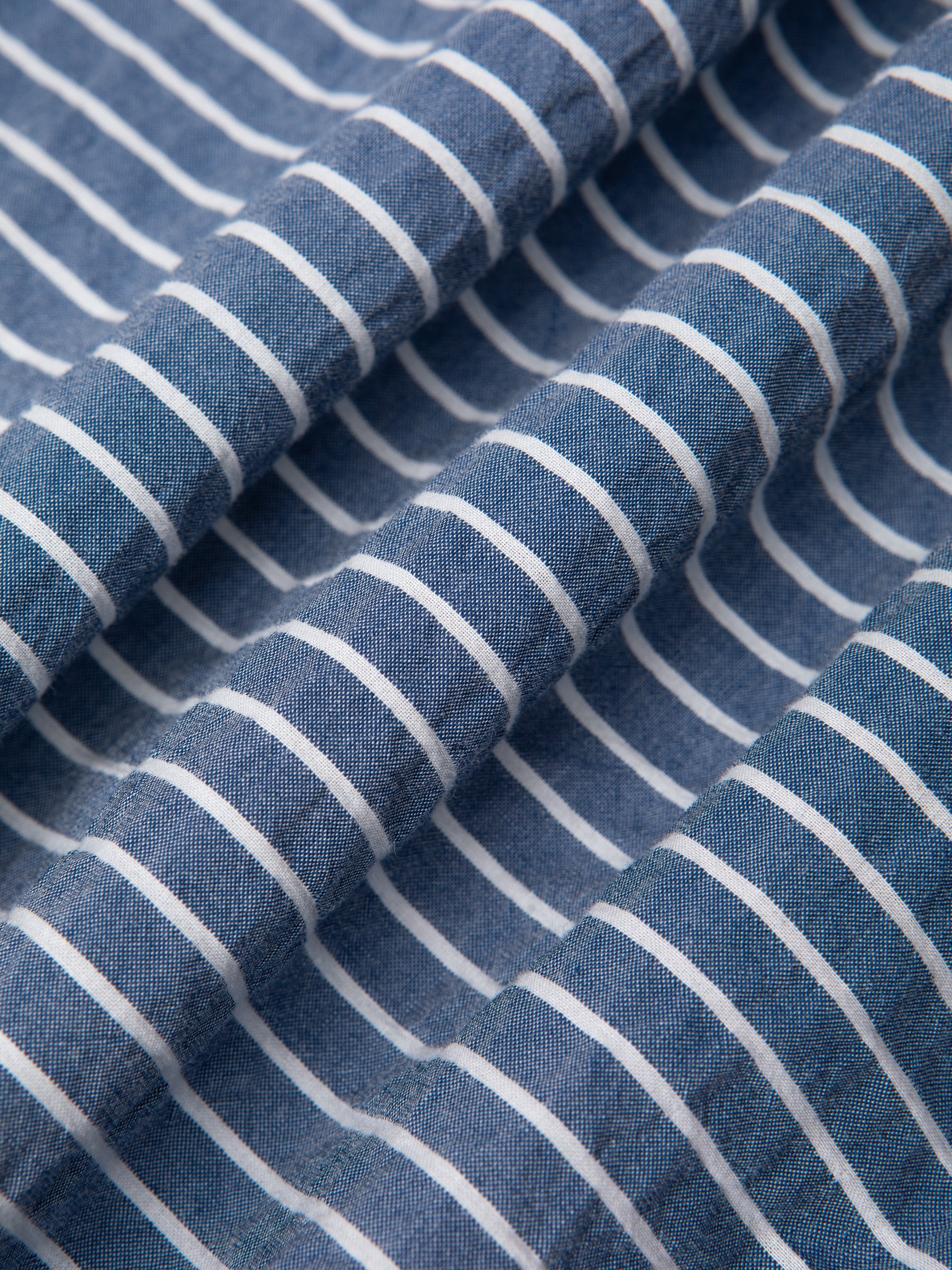 A cotton seersucker shirting fabric in blue with white stripes.