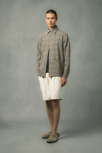 A man wearing a check overshirt and white shorts from menswear designer KESTIN.