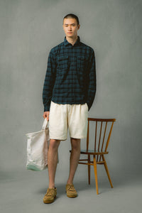 A model stood by a chair, wearing shorts and a shirt by designer brand KESTIN.