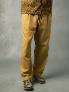 A pair of relaxed fit tan trousers from KESTIN, worn on a model.