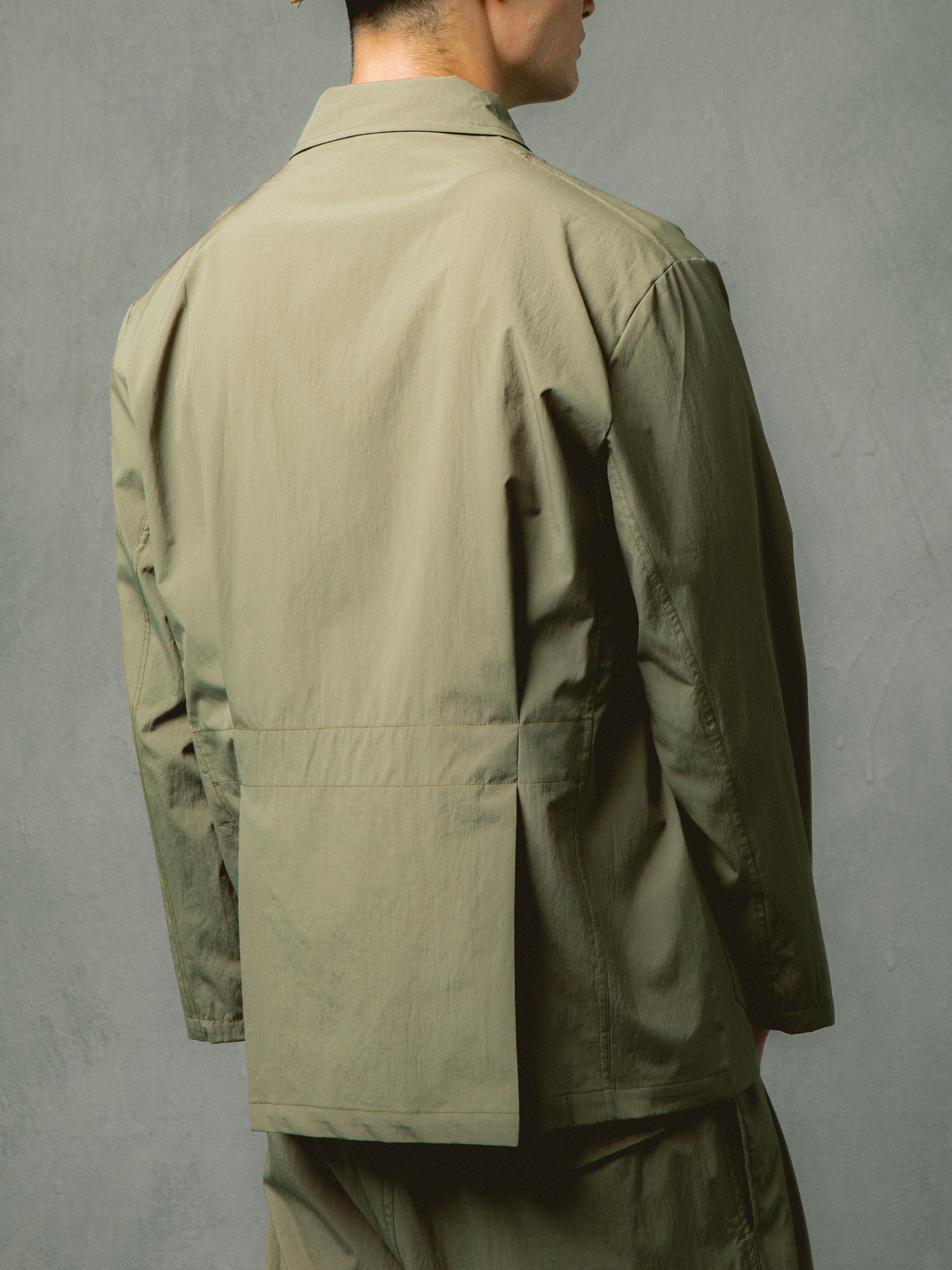 The rear profile of the KESTIN Port Blazer in olive green, featuring a banded waist.