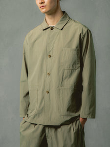 A model wearing an olive green jacket made from a technical fabric.