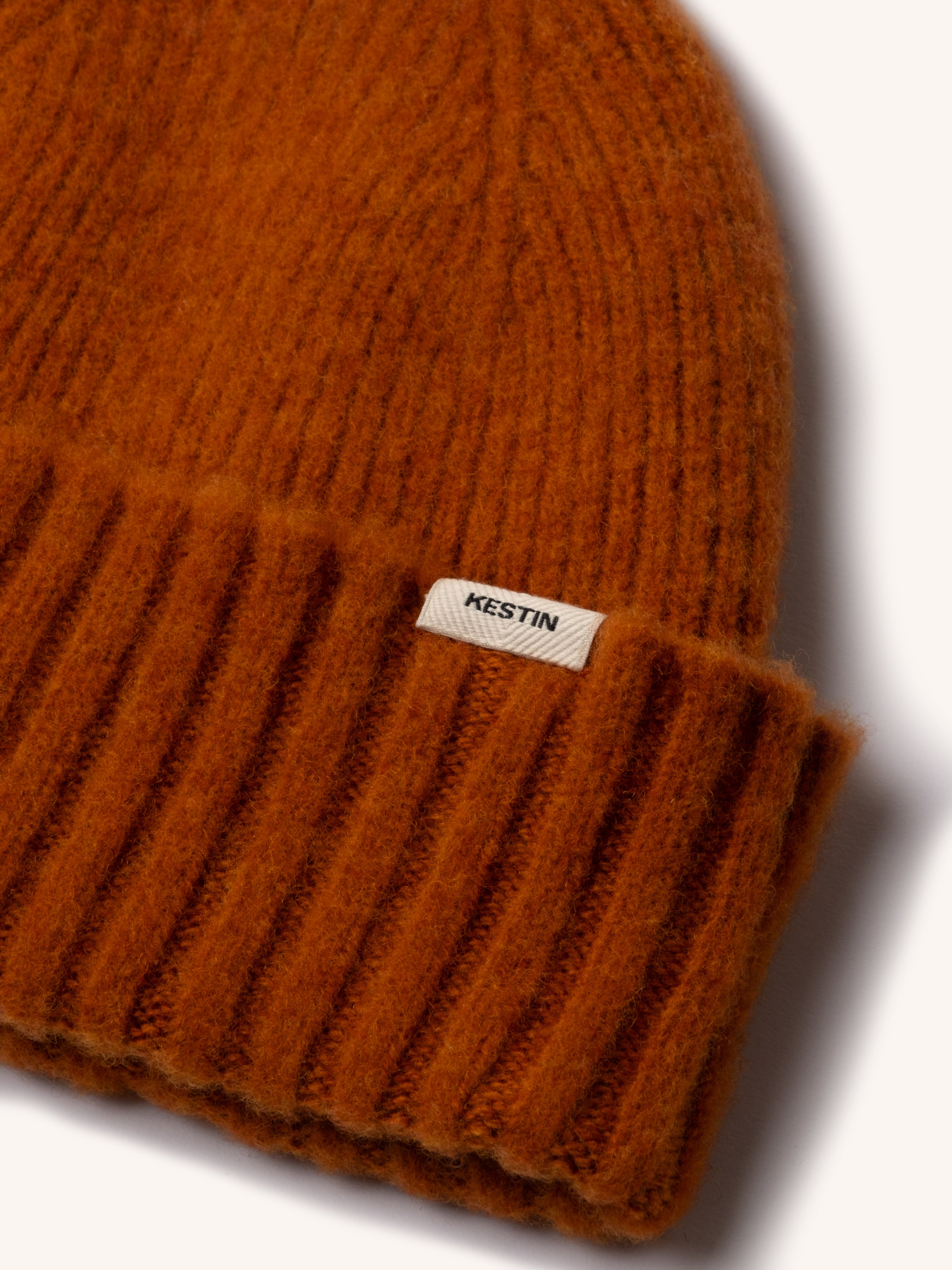 The woven logo tag to the KESTIN Balloch Beanie in orange.