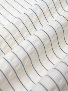 A white seersucker fabric with a thin blue stripe pattern.