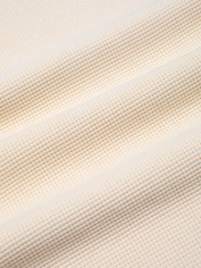An ecru white waffle knit fabric, made from 100% cotton.